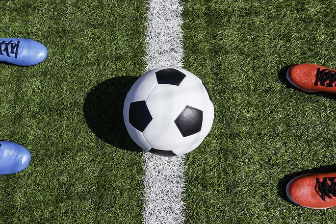 Blue and Red Football Boots Either Side of Ball