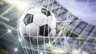 Football Hitting Goal Net Against Bright Stadium