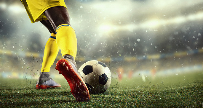 Footballer Yellow Kit Kicking Ball
