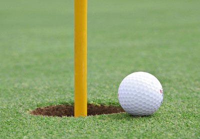Golf Ball Next to Hole with Yellow Pin