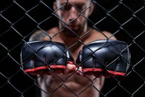 MMA Fighter Holding Gloves Against Cage