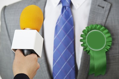 Politician with Green Rosette Interviewed by Journalist