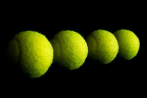Four Tennis Balls Against Black Background