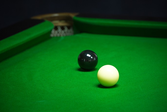 White and Black Snooker Balls in Corner of Table